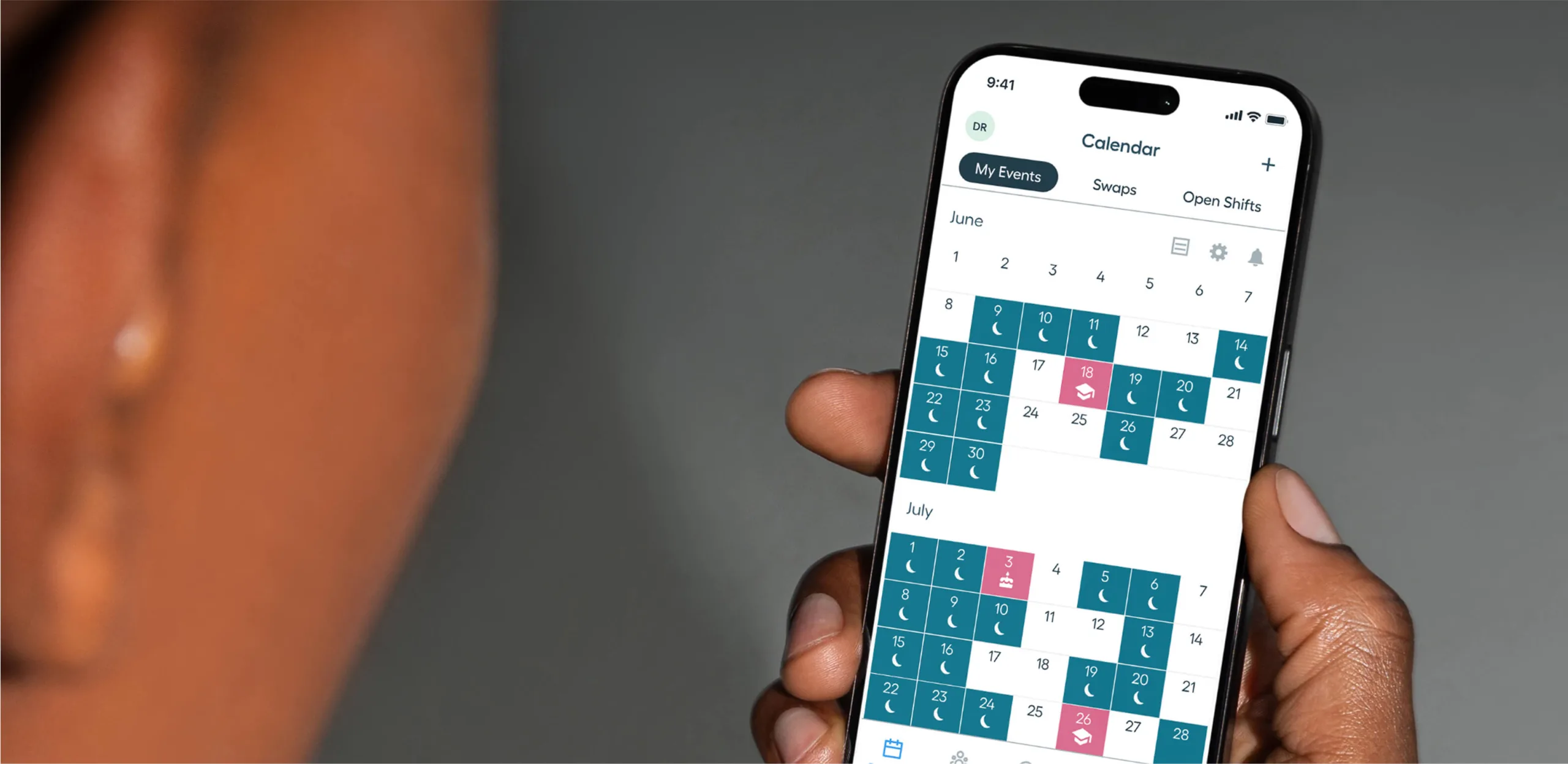 A person holds a smartphone showing a calendar app with highlighted dates in June and July, displaying various events and availability statuses.