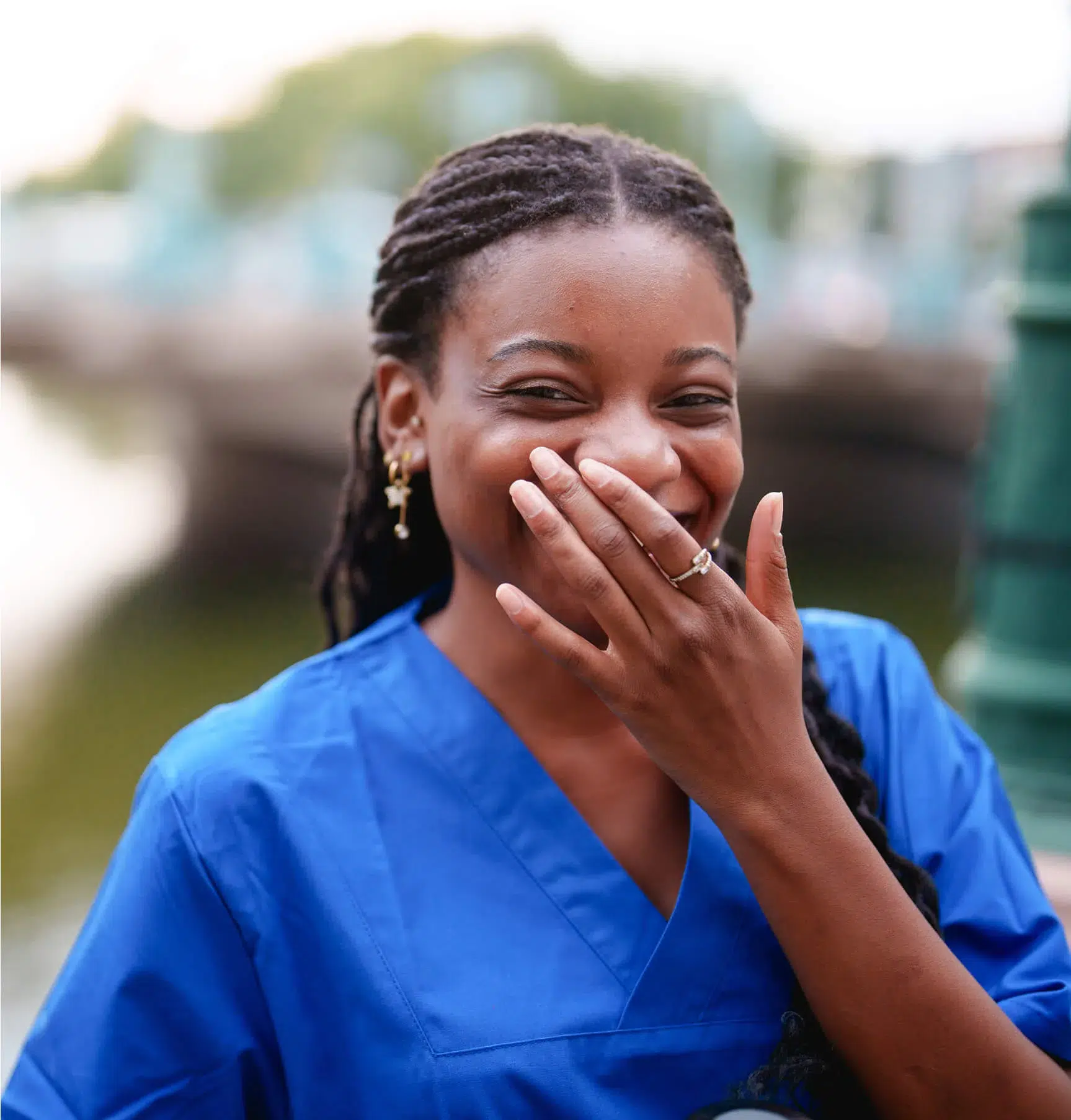 A woman in blue scrubs laughing.
