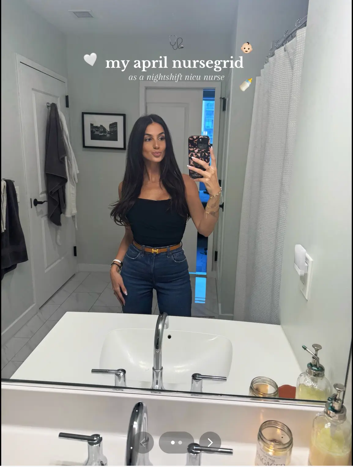 A woman stands in a bathroom taking a mirror selfie. Text above her reads, my april nursegrid as a nightshift nicu nurse. The bathroom is tidy, with towels and items on the sink.